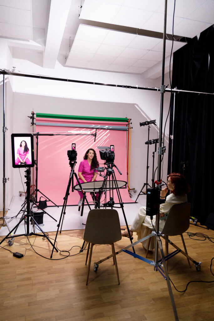 Ședință de brand personal la Alt Nivel: clientă pe fundal roz, camera, prompterul și moderatoarea alături